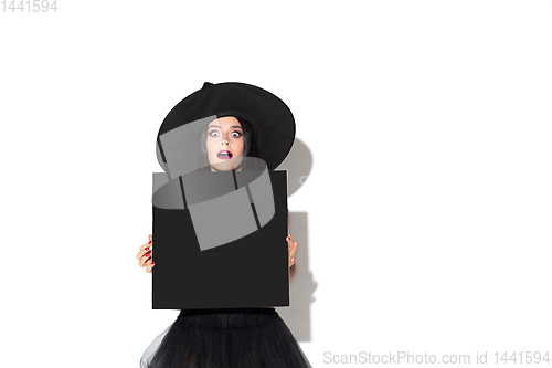 Image of Young woman in hat and dress as a witch on white background