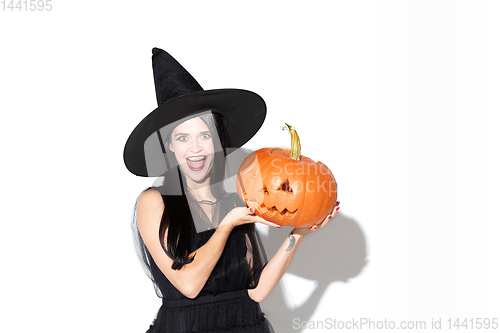 Image of Young woman in hat and dress as a witch on white background