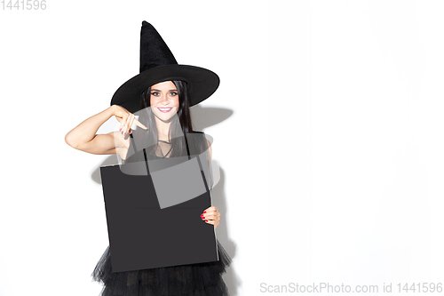 Image of Young woman in hat and dress as a witch on white background