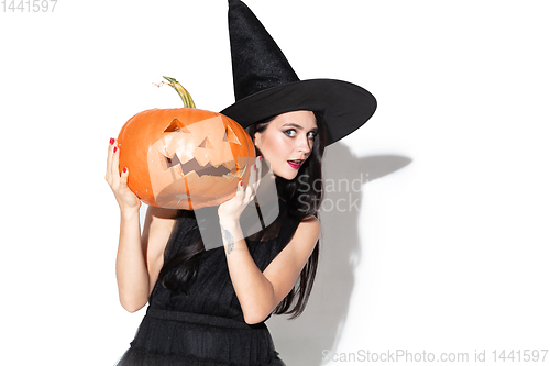 Image of Young woman in hat and dress as a witch on white background