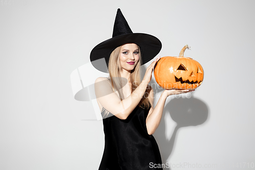 Image of Young woman in hat as a witch on white background