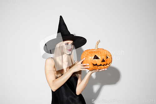 Image of Young woman in hat as a witch on white background