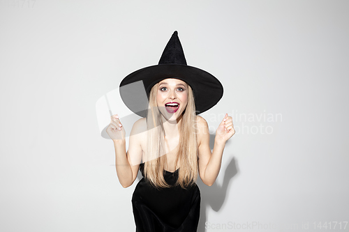 Image of Young woman in hat as a witch on white background