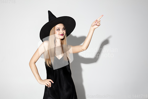 Image of Young woman in hat as a witch on white background