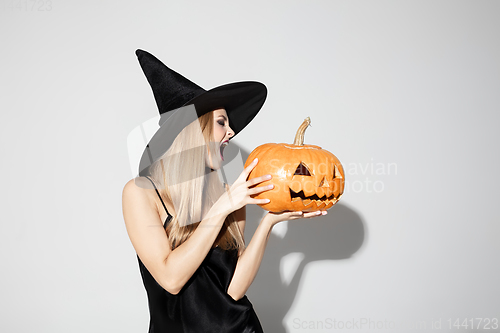 Image of Young woman in hat as a witch on white background