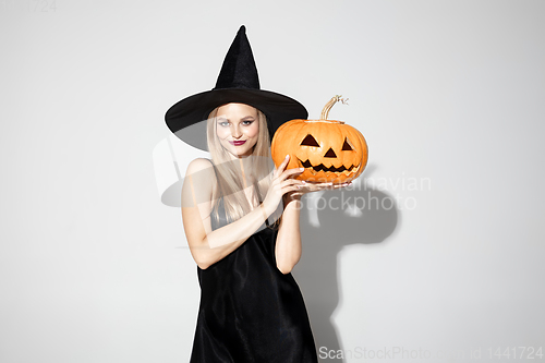Image of Young woman in hat as a witch on white background
