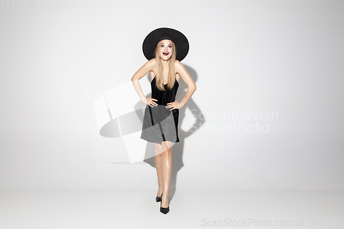 Image of Young woman in hat as a witch on white background