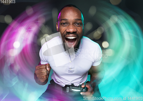 Image of Enthusiastic gamer. Joyful young man holding a video game controller