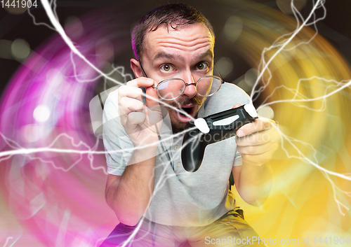 Image of Enthusiastic gamer. Joyful young man holding a video game controller