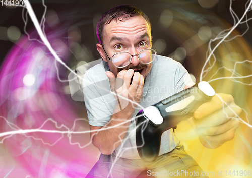 Image of Enthusiastic gamer. Joyful young man holding a video game controller