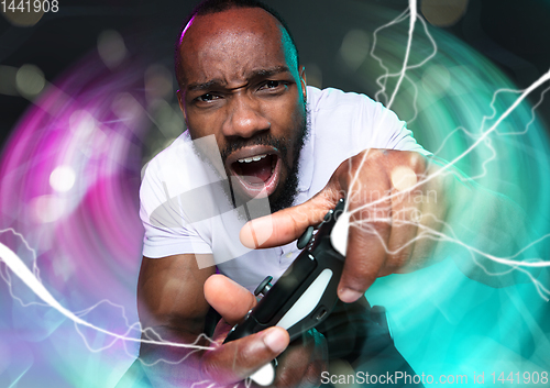 Image of Enthusiastic gamer. Joyful young man holding a video game controller