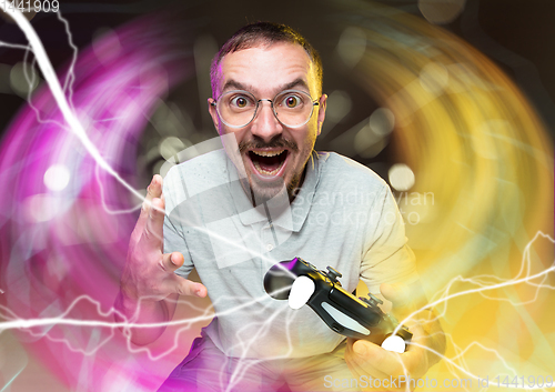 Image of Enthusiastic gamer. Joyful young man holding a video game controller