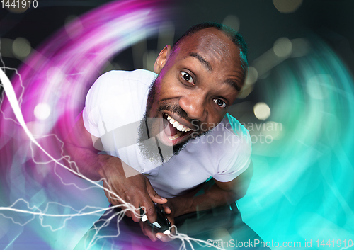 Image of Enthusiastic gamer. Joyful young man holding a video game controller