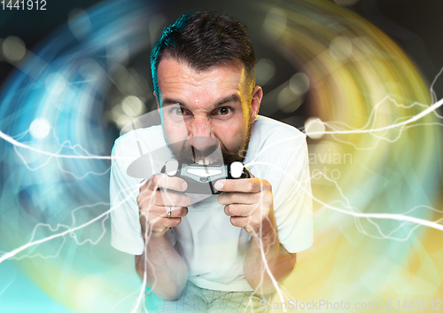 Image of Enthusiastic gamer. Joyful young man holding a video game controller