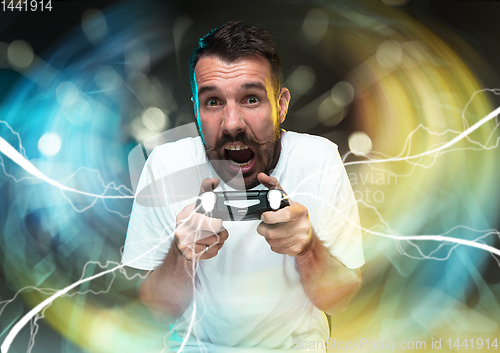 Image of Enthusiastic gamer. Joyful young man holding a video game controller