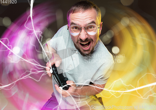 Image of Enthusiastic gamer. Joyful young man holding a video game controller