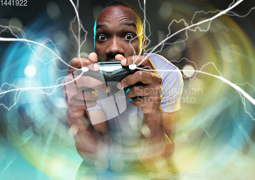 Image of Enthusiastic gamer. Joyful young man holding a video game controller