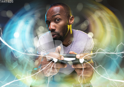 Image of Enthusiastic gamer. Joyful young man holding a video game controller