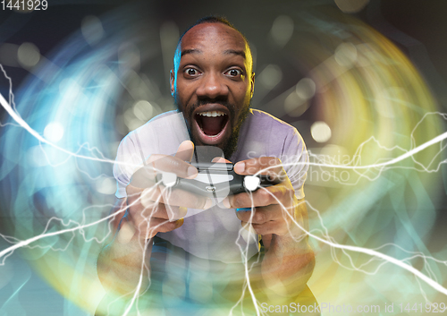 Image of Enthusiastic gamer. Joyful young man holding a video game controller