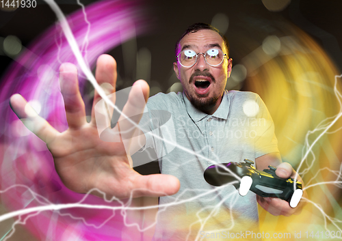 Image of Enthusiastic gamer. Joyful young man holding a video game controller