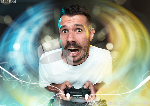 Image of Enthusiastic gamer. Joyful young man holding a video game controller