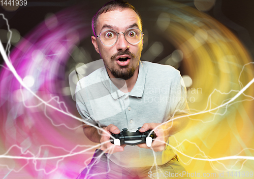 Image of Enthusiastic gamer. Joyful young man holding a video game controller