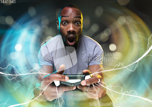 Image of Enthusiastic gamer. Joyful young man holding a video game controller