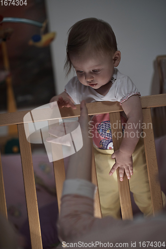 Image of cute little one year old baby and making first steps in bed