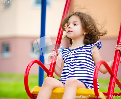 Image of Young happy girl is swinging in playground