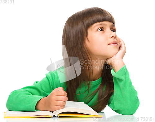 Image of Young girl is daydreaming while reading book