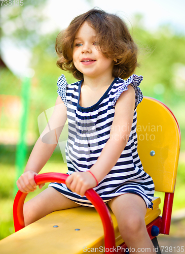 Image of Young happy girl is swinging in playground