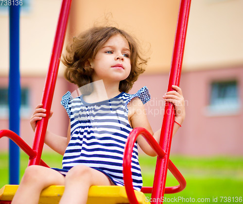Image of Young happy girl is swinging in playground