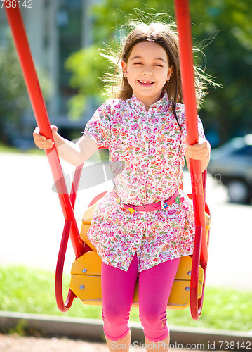 Image of Young happy girl is swinging in playground