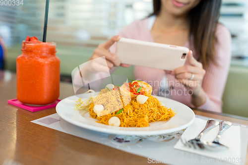 Image of Woman taking photo on the fried noodles