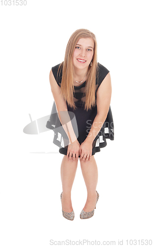 Image of Happy woman in a short black dress bending