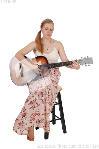 Image of Woman sitting with her guitar and singing