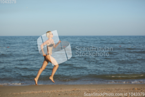 Image of Side view of a woman running on the beach with the horizon and sea in the background