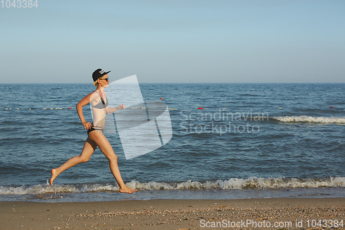 Image of Sexy and happy beautiful woman in bikini running on the beach. In a cap with the inscription queen. Film effect.