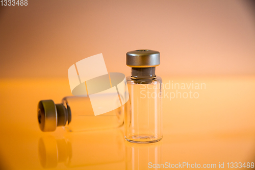 Image of two vaccine bottles on orange background