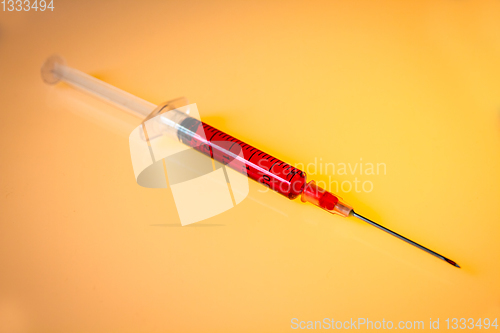 Image of Syringe with blood on orange background