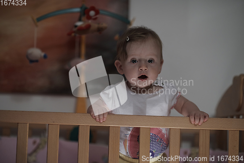 Image of cute little one year old baby and making first steps in bed