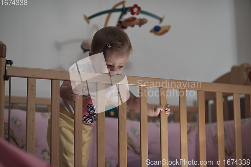 Image of cute little one year old baby and making first steps in bed