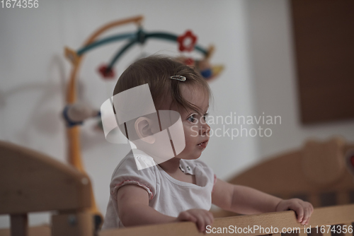 Image of cute little one year old baby and making first steps in bed