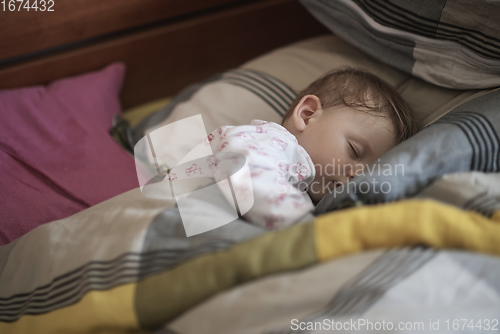 Image of newborn baby sleeping at home in bed