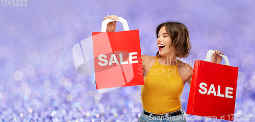 Image of happy young woman with shopping bags on sale