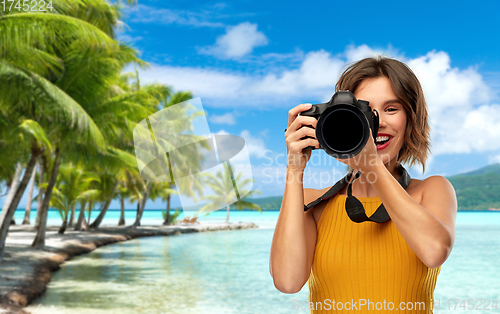 Image of happy woman photographer with camera on beach