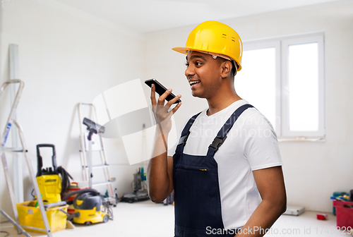 Image of happy indian builder recording voice on smartphone