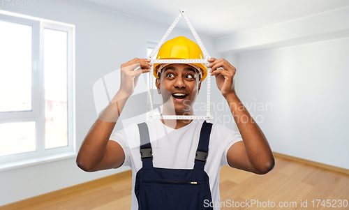 Image of happy indian builder with ruler in shape of home