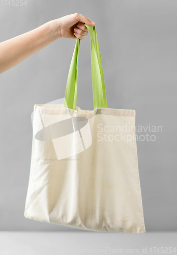 Image of hand holding reusable canvas bag for food shopping