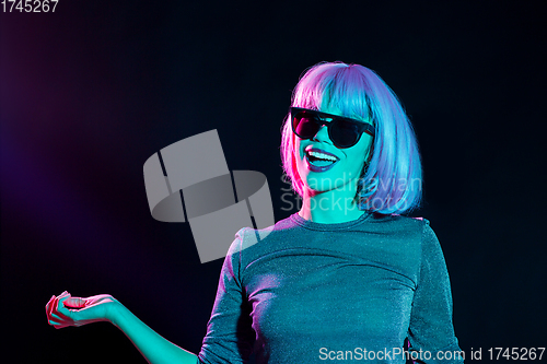 Image of happy woman in pink wig and sunglasses dancing